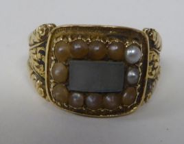 An antique gold coloured metal mourning ring with an engraved shank, set with seed pearls