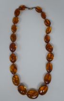 An amber coloured graduated oval bead necklet, the dog-clip clasp stamped 925