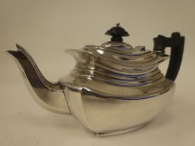 An Edwardian bachelors silver teapot of panelled, oval form with a swept spout, insulated handle and