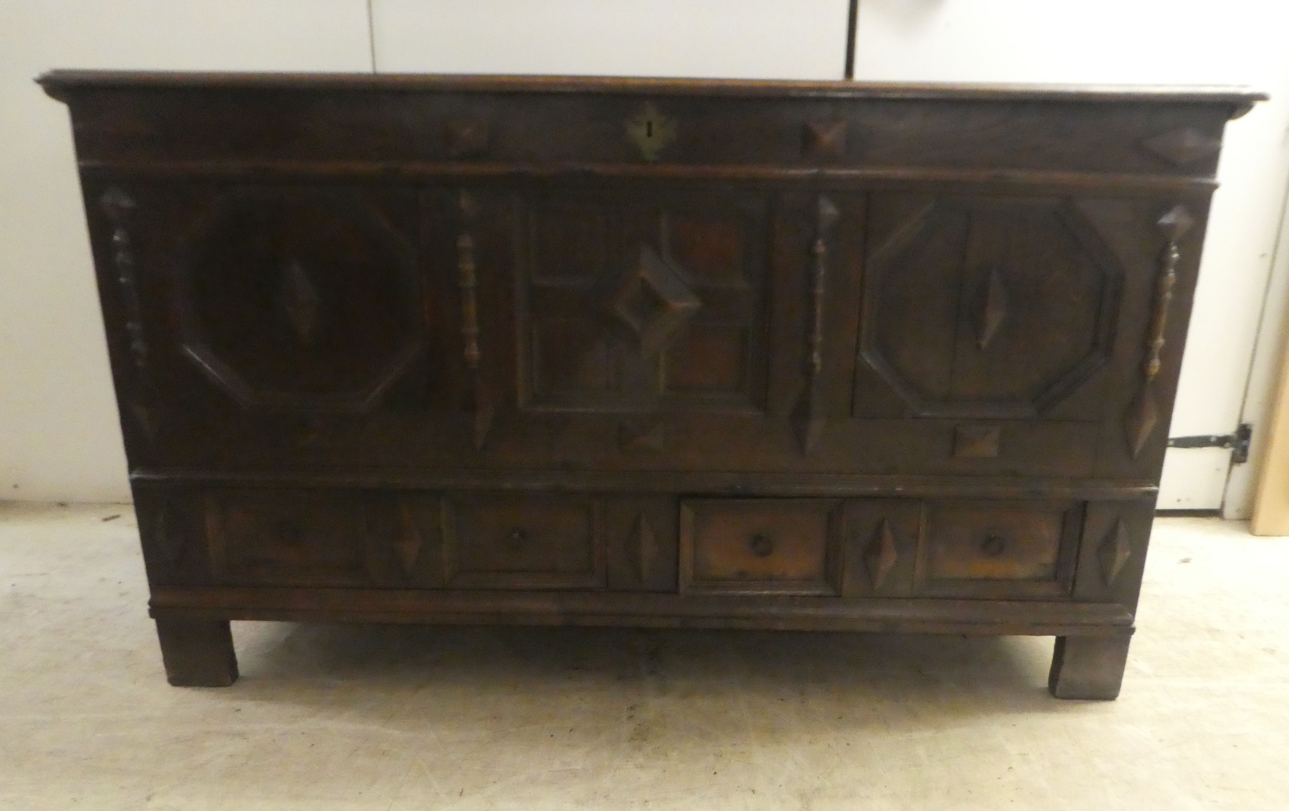 A late 18thC oak coffer with straight sides and a hinged lid, a panelled front and two drawers,
