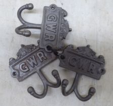 A set of three cast iron, twin handled coat hooks, branded for 'GWR'  each 4"w