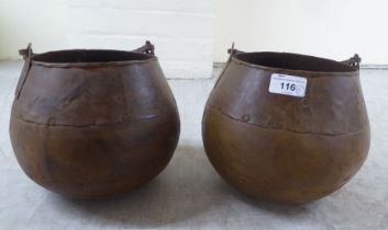 A pair of rivetted cast metal hanging cooking pots