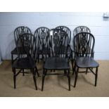 Seven ebonised oak wheel back and solid-seat dining chairs.