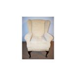 A modern cream upholstered wingback armchair.