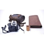 A pair of brass lacquered and leather binoculars; and a leather-cased travelling vanity set.