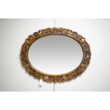 A c1930 carved oak oval wall hanging mirror