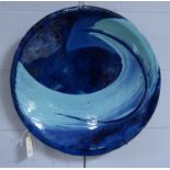 A contemporary blue glazed terracotta charger, of circular form, with stylised wave decoration.