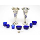 A pair of silver vases and blue glass condiment liners