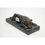 A bronze figure of a bulldog, modelled lying down, raised over a marble block base