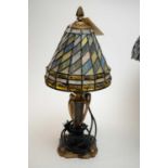 A stained leaded glass style table lamp, with iridescent shade over dragon-scale style base.