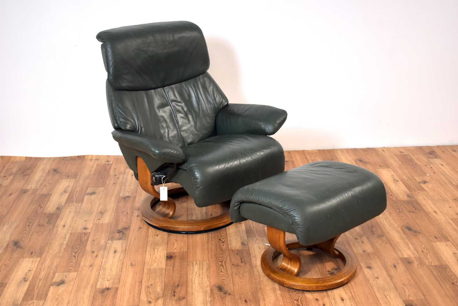 A contemporary Ekornes Stressless leather reclining armchair and matching ottoman footstool