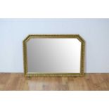 A contemporary gilt wall mirror of rectangular form with canted edges to the top corners