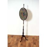 A Victorian mahogany pole screen with tapestry oval panel