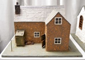 A unique scratch made model dolls house in the form of a stone cottage