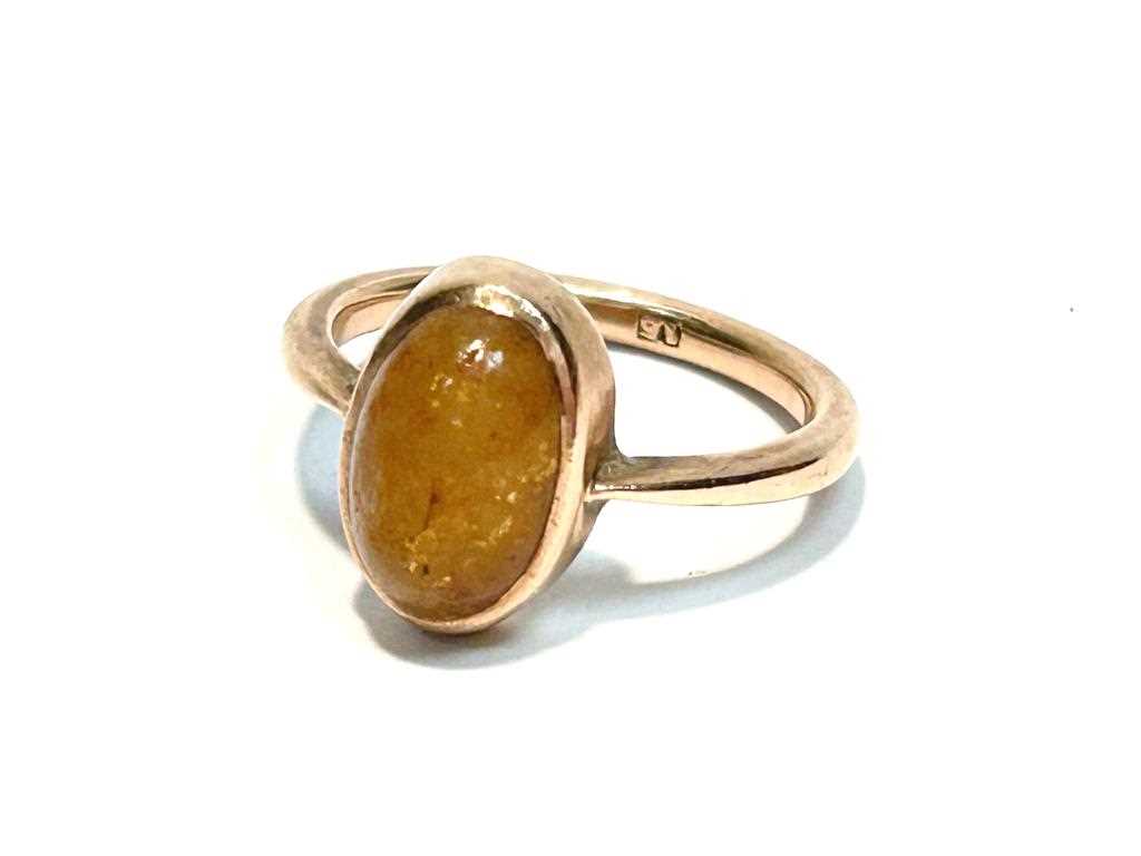A yellow stone cabochon ring