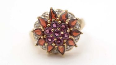 A diamond and red gemstone flower cluster ring