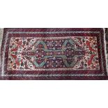 A vintage Persian Hamadan rug, the geometric medallion designs on dark blue ground within