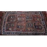 An old Persian design Shiraz rug, the design of eight large boteh on brown ground within