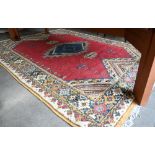 Turkish carpet geometric design with blue diamond medallion on red ground, cream and mustard