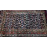 A worn antique Kurdish rug, repeating stylised floral motif on dark blue ground, rosette borders,