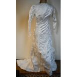 A vintage cream wedding gown in heavy satin with printed floral sprigs, full length with buttoned
