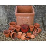 A terracotta square planter with rose motif to/with assorted terracotta plant pots and a weathered