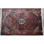 A Persian Bidjar rug, intricate floral design on red/blue ground with guarded conforming borders