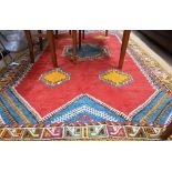 A Moroccan carpet, geometric design on red ground repeating colourful borders, 240 x 160 cm