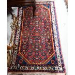 A pair of Persian Hamadan rugs, each with all-over rosettes/floral designs on red ground, blue and