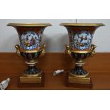 Pair of Paris porcelain urns, the reserves painted with mandarins, 26 cm high, on later wooden