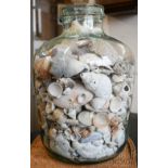 A large glass bottle containing seashells