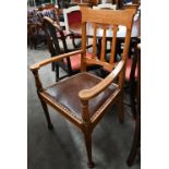 An Arts & Crafts oak elbow chair with studded brown leather padded seat, in the manner of Liberty