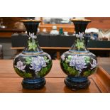 Pair of Chinese cloisonné vases with floral decoration on a black ground, on carved wood bases, 28