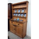 An antique waxed pine dresser, the raised plate rack with three shelves on a base with two drawers