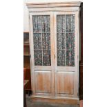A limewashed pine wardrobe with part glazed and panelled doors enclosing shelf and hanging rail