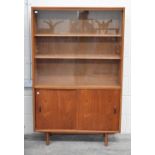 A mid century teak bookcase circa 1960, with sliding glass doors enclosing two adjustable shelves