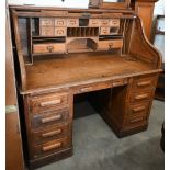 A large early 20th century oak roll-top desk, the sliding tambour panel enclosing complex fitted