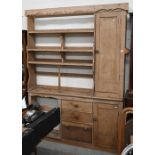An antique pine shallow dresser with an arrangement of open shelves, drawers and panelled cupboards,