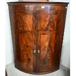 A 19th century mahogany barrel front hanging corner cabinet with two doors and brass floral cast
