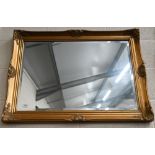 A bevelled wall mirror in decorative moulded gilt frame, 90 cm wide x 64 cm high
