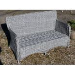 An all-weather grey wicker style two seat garden sofa, c/w cover