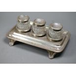 A George IV silver inkstand with three silver-topped cut glass pots, with reeded rim and bracket