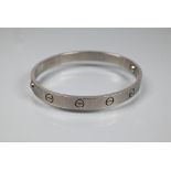 Cartier - an oval 'love' bangle, white metal stamped 750, etched Cartier inscription numbered M.