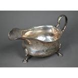 An Edwardian silver pot-bellied sauce boat in the Georgian manner, with scroll handle and pad