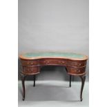 An Edwardian walnut kidney shaped desk with inset leather top over an arrangement of five drawers,