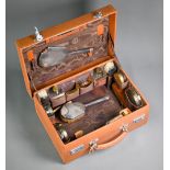 A pigskin toilet case fitted with a silver brush set, glass jars with gilt metal covers and
