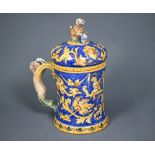 A Venetian maiolica tankard & cover, painted with grotesques and putti in ochre and yellow on a blue