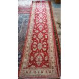 A contemporary Agra runner, soft red stylized floral design on pink and camel ground, 635 x 80 cm