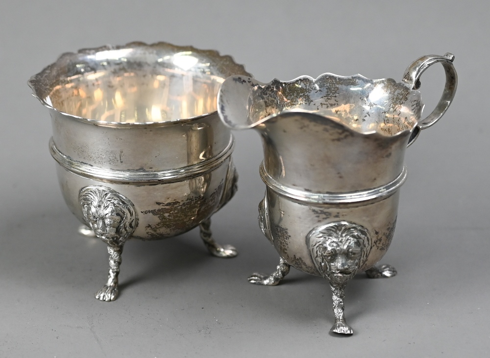 An Edwardian silver cream & sugar pair, with cut rims, scroll handles and lion-mask monopodia,