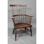 An antique elm seat comb-back chair, raised on turned legs united by an H-stretcher